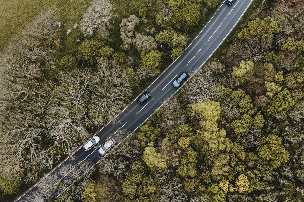 Aerial view of two lane highway lined by trees. 